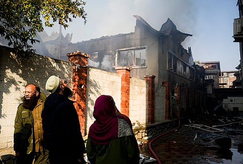 People gather as smoke billows after a major fire broke out at a blanket godown adjacent to Medicare Hospital, in Srinagar, Jammu and Kashmir. 