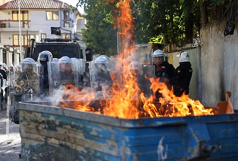 Riot police stand in formation behind a burning garbage can during an anti-government rally, in Tirana, Albania, Saturday, Oct. 24, 2026. 
