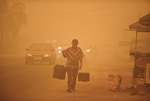 A street vendor walks amid thick haze from wildfires in Palangkaraya, Central Kalimantan, Indonesia, Saturday, Oct. 24, 2026. 

