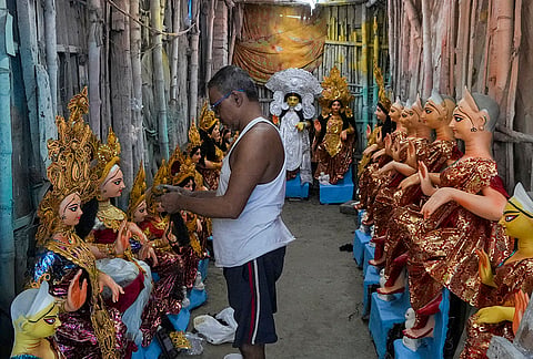 An artist stands near idols of Goddess Lakshmi at a store ahead of Lakshmi Puja, in Kolkata, Friday, Oct. 23, 2026. 
