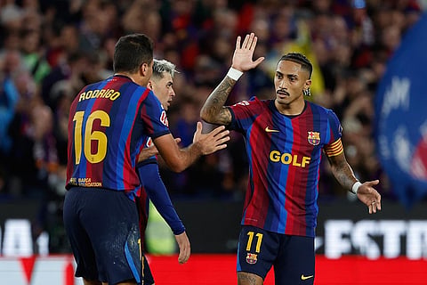 Barcelona's Raphinha, right, celebrates Barcelona's Rodrigo after scoring his side's opening goal during a Spanish La Liga soccer match between FC Barcelona and Real Madrid in Barcelona, Spain, Sunday, Oct. 25, 2026.