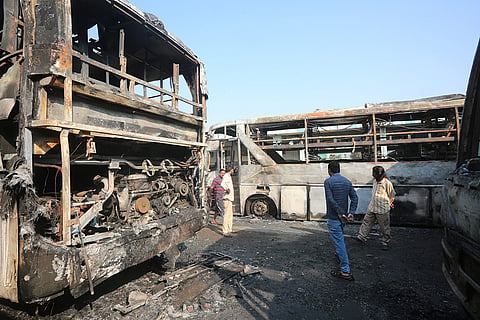 People gather near the charred remains of buses after a fire broke out at a Inter State Bus Terminal (ISBT) on Sunday, in Bhopal.