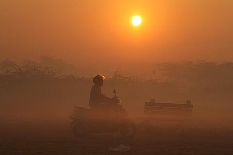 A commuter moves amid hazy conditions during sunrise, in Gurugram.