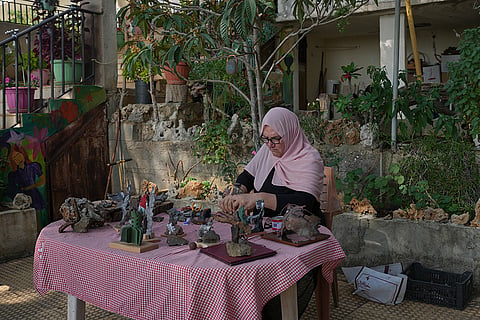 Visual artist Lina Jouni works on an artwork made from shrapnel collected from Israeli military munitions at her home in the village of Roumin, southern Lebanon, Sunday, Oct. 25, 2026.