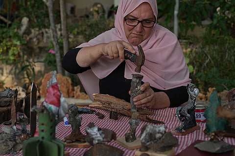 Visual artist Lina Jouni uses a hammer to shape a piece of shrapnel collected from Israeli military munitions as she works on an artwork at her home in the village of Roumin, southern Lebanon, Sunday, Oct. 25, 2026.