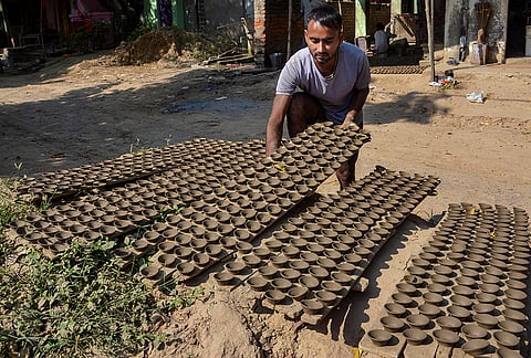 An artisan arranges earthen lamps to dry in the sun ahead of 'Diwali' festival, in Mirzapur, Uttar Pradesh.