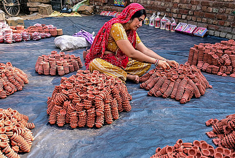 A woman arranges earthen lamps for sale ahead of the ‘Diwali’ festival, in Bikaner, Tuesday, Oct. 13, 2026. 
