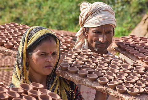 Potters carry earthen lamps for drying in the sun ahead of Diwali, in Moradabad, Uttar Pradesh, Monday, Oct. 26, 2026. 