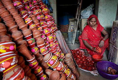 An artisan dips an earthen lamp into paint for sale ahead of the ‘Diwali’ festival, in Kolkata, Sunday, Oct. 25, 2026. 
