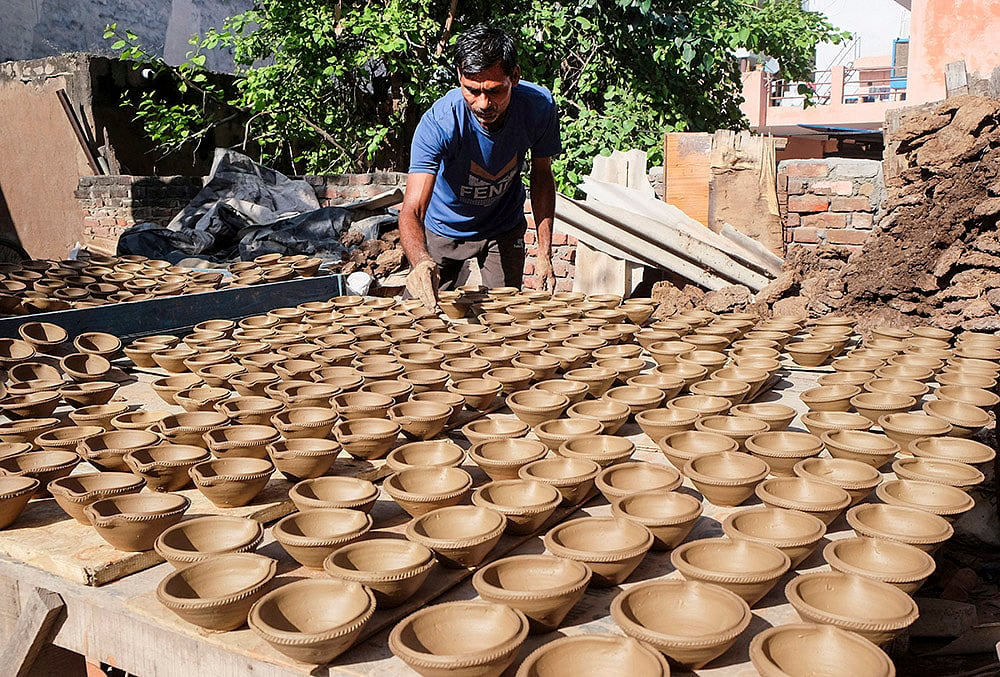A potter moulds an earthen lamp ahead of Diwali festival