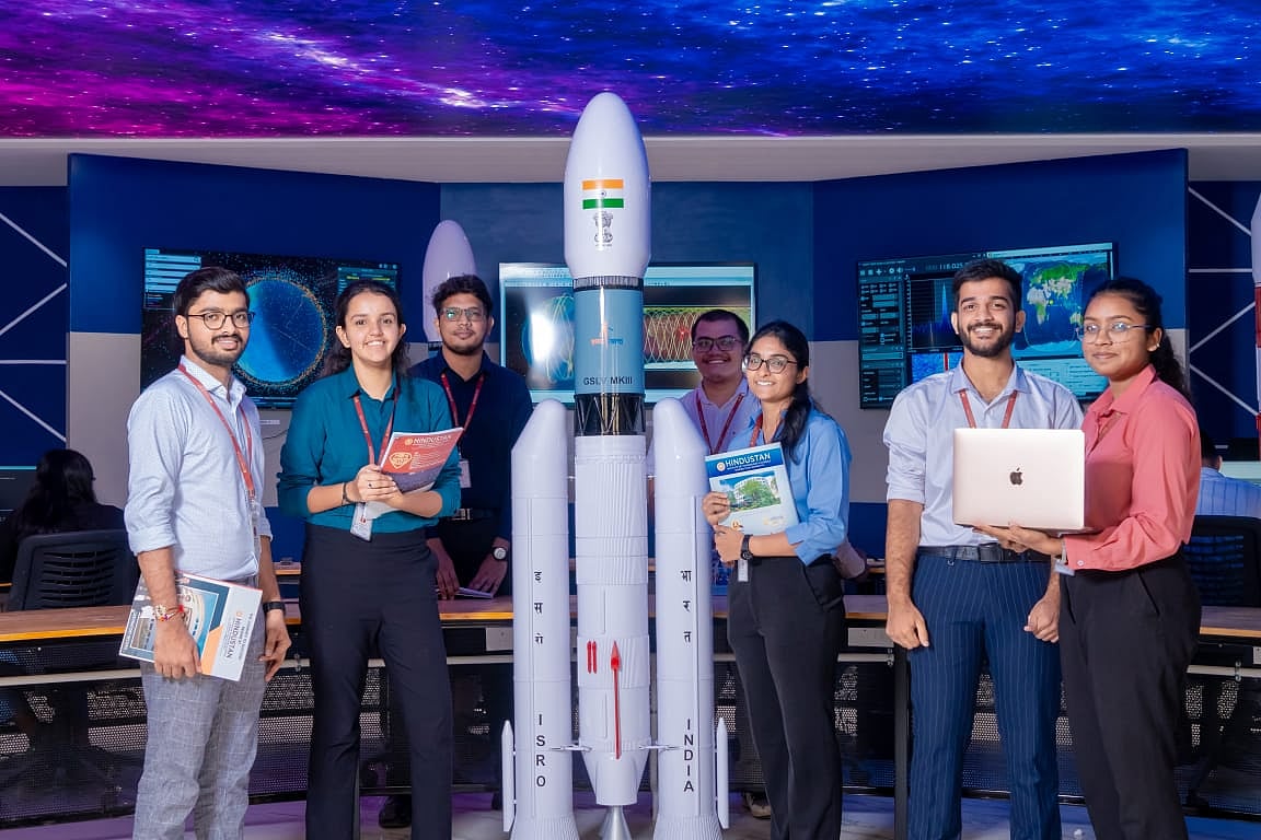 Hindustan University students posing with a model rocket inside a space control room simulator