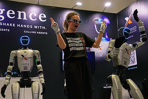 A woman dances beside humanoid robots at the Legend Robotics stand at the Dubai AI Festival in Dubai, United Arab Emirates, Tuesday, Oct. 27, 2026.