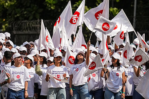 People wave flags with the Jio logo after the listing ceremony of Jio Platforms Limited during its IPO, near National Stock Exchange (NSE) in Mumbai, Wednesday, Oct. 28, 2026.