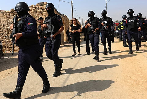 Armed Jordanian police officers patrol near mourners during the funeral of victims killed in an attack on a Greek Orthodox church in Karak, Jordan, Sunday, Oct. 25, 2026. 