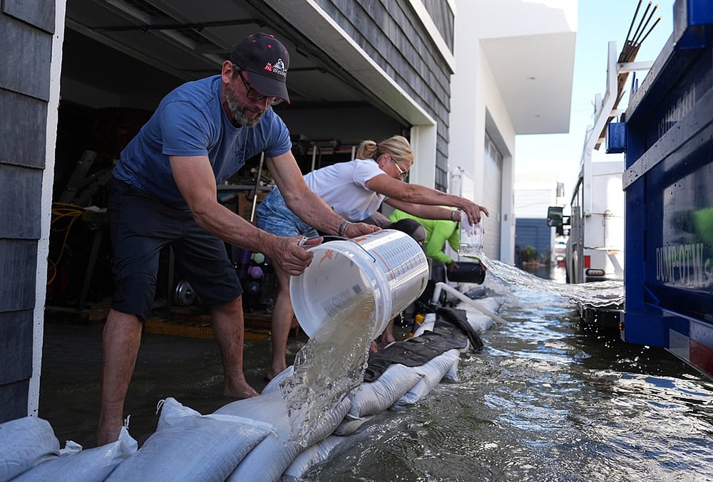 Members of the Deakins family remove floodwater from their garage in Huntington Beach, California, Wednesday, Oct. 28, 2026.  - | Photo: AP/Jae C. Hong