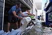 In Photos: King Tides Bring The Sea Into Streets On Both US Coasts | Photo: AP/Jae C. Hong : Members of the Deakins family remove floodwater from their garage in Huntington Beach, California, Wednesday, Oct. 28, 2026.