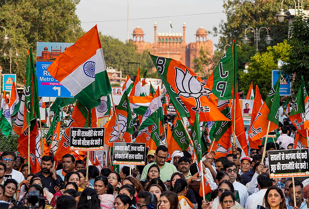 BJP leaders, workers, and supporters carry national flags and party banners with the Red Fort in the background during the 'Loktantra Bachao, Arajakta Hatao' protest march, at Chandni Chowk, in New Delhi, Wednesday, Oct. 28, 2026. The march commenced from Shri Jain Lal Mandir near the Red Fort and concluded at Town Hall Chowk as part of a nationwide counter-campaign.  - | Photo: PTI/Salman Ali