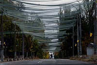 In Photos: Ukraine Draped In Anti-Drone Netting | Photo: AP/Evgeniy Maloletka : A woman walks beneath anti-drone nets stretched over a street during a local ceasefire related to a humanitarian aid mission in Oleshky, in Kherson, Ukraine, Wednesday, Oct. 28, 2026.