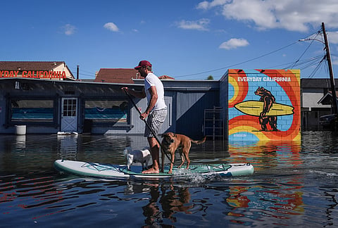 James Hays paddleboards with two dogs along a flooded section of Pacific Coast Highway in Huntington Beach, California, Wednesday, Oct. 28, 2026. 
