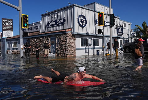 A man surfs through floodwaters in Huntington Beach, California, Wednesday, Oct. 28, 2026. 
