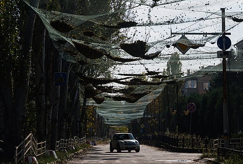 A car rides a road beneath anti-drone nets stretched over a street during a local ceasefire related to a humanitarian aid mission in Oleshky, in Kherson, Ukraine, Wednesday, Oct. 28, 2026.
