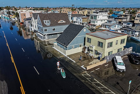 James Hays pulls his paddleboard through floodwaters on the Pacific Coast Highway in Huntington Beach, California, Wednesday, Oct. 28, 2026. 