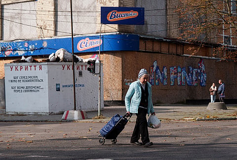 A woman walks across a street beneath anti-drone nets stretched over a street during a local ceasefire related to a humanitarian aid mission in Oleshky, in Kherson, Ukraine, Wednesday, Oct. 28, 2026. 
