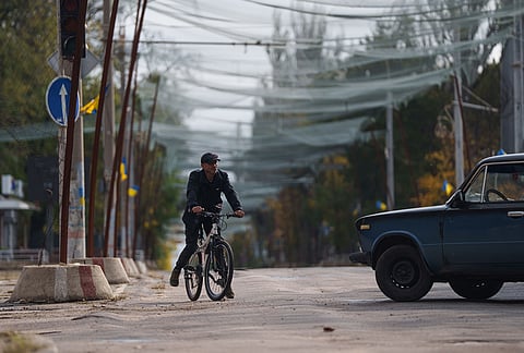 A local man rides a bicycle beneath anti-drone nets stretched over a street during a local ceasefire related to a humanitarian aid mission in Oleshky, in Kherson, Ukraine, Wednesday, Oct. 28, 2026. 
