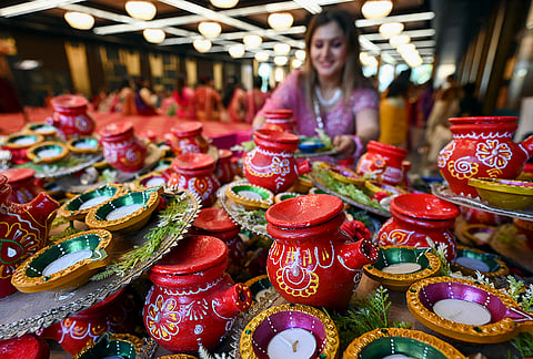 A member of Madhavi Agrasen Mahila Sangathan arranges earthen pots during an event to celebrate 'Karva Chauth' festival, in Ahmedabad, Gujarat, Wednesday, Oct. 28, 2026. 
