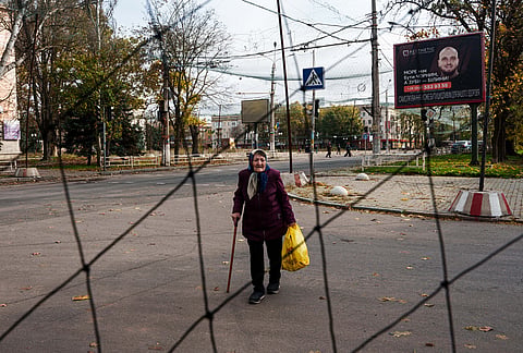 An elderly woman walks beneath anti-drone nets stretched over a street during a local ceasefire related to a humanitarian aid mission in Oleshky, in Kherson, Ukraine, Wednesday, Oct. 28, 2026. 
