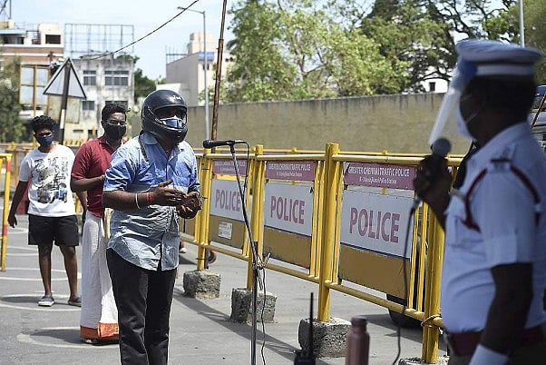 A traffic policeman maintains social distancing as he questions commuters on a mic for violating an intensified lockdown, to curb the spread of coronavirus disease, in Chennai