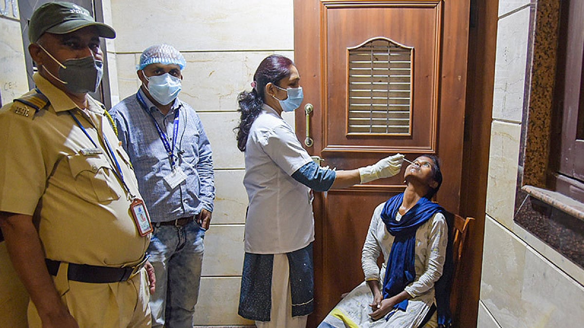 A medic from NMMC Health Department collects a swab sample of a woman for COVID-19 test.