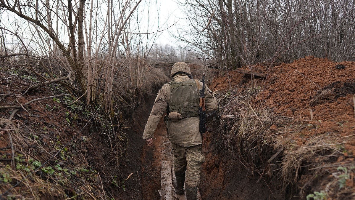 A Ukrainian serviceman walks in a trench at his position at the line of separation between Ukraine-h