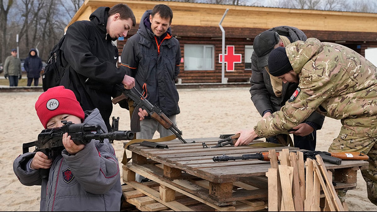 A boy plays with a weapon as an instructor shows a Kalashnikov assault rifle in Kyiv, Ukraine.