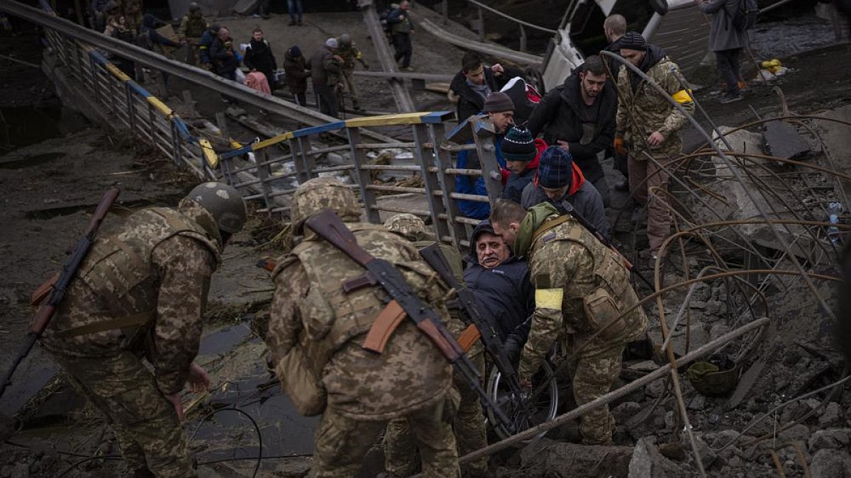     Ukrainian soldiers help a man on a wheelchair as people try to flee in Kyiv, Ukraine.