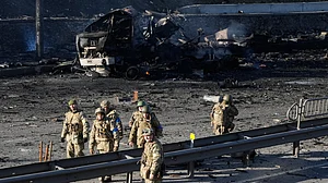 Ukrainian soldiers walk past debris of a burning military truck on a street in Kyiv, Ukraine.