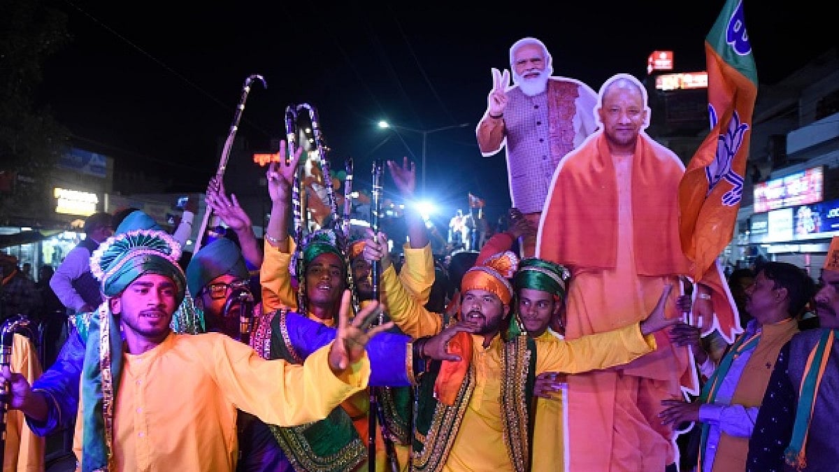 BJP supporters carry PM Narendra Modi and Yogi Adityanath cutouts during a road show campaign. 