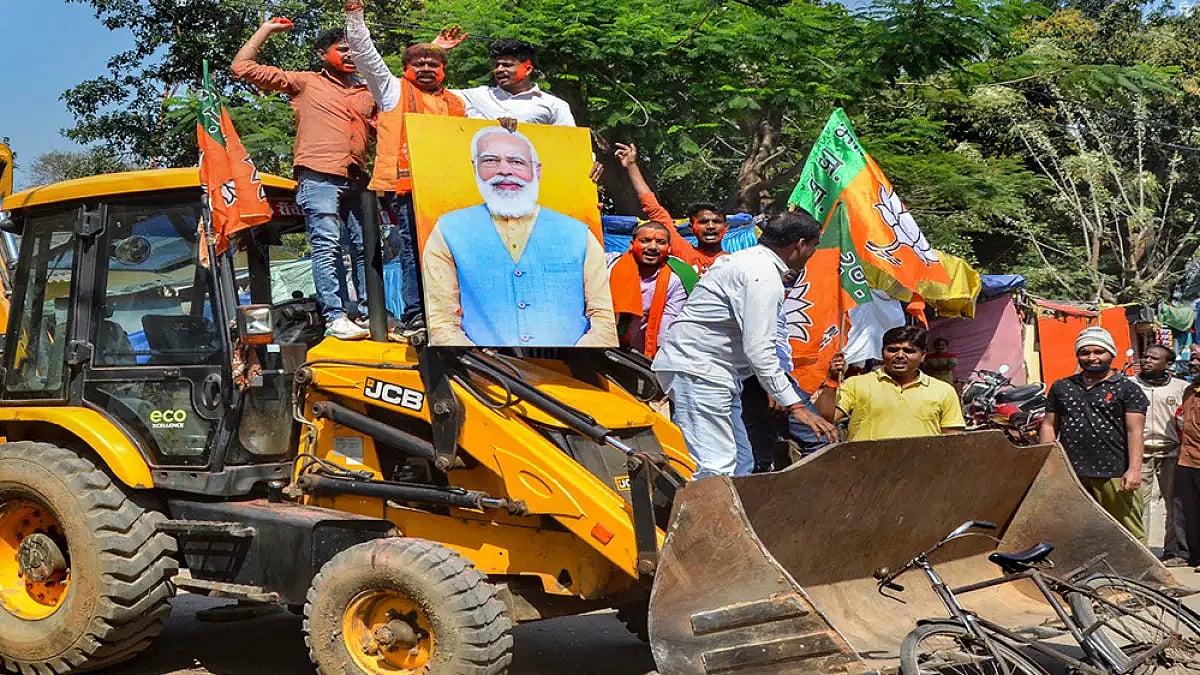 BJP supporters holding party flags ride a bulldozer in celebration, party heads to landslide victory