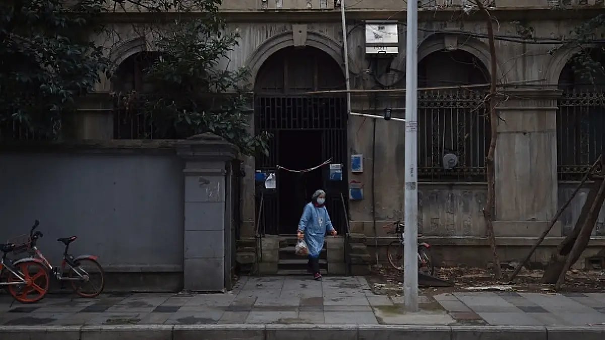 A masked woman takes a bag of garbage out of a residential building in Wuhan in Chinas Hubei