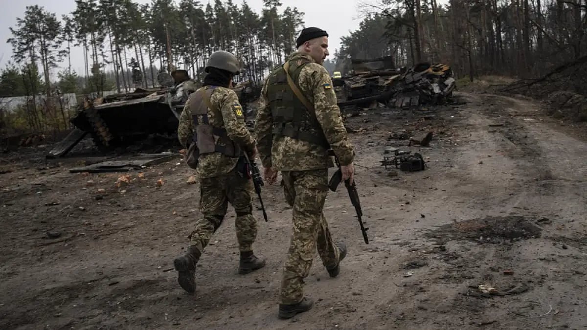 Ukrainian soldiers walk next to destroyed Russian tanks in the outskirts of Kyiv, Ukraine.