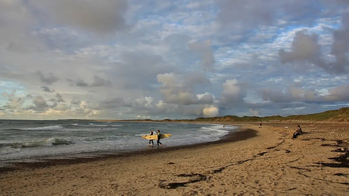 Surfers heading out to sea in Klitmoller, Denmark