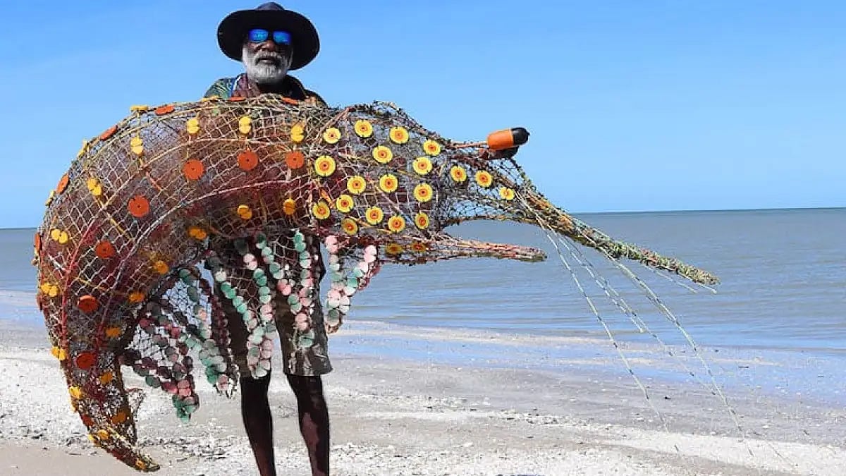 Pormpuraaw community's Sid Bruce Short Joe with a sculpture made from ghost nets 