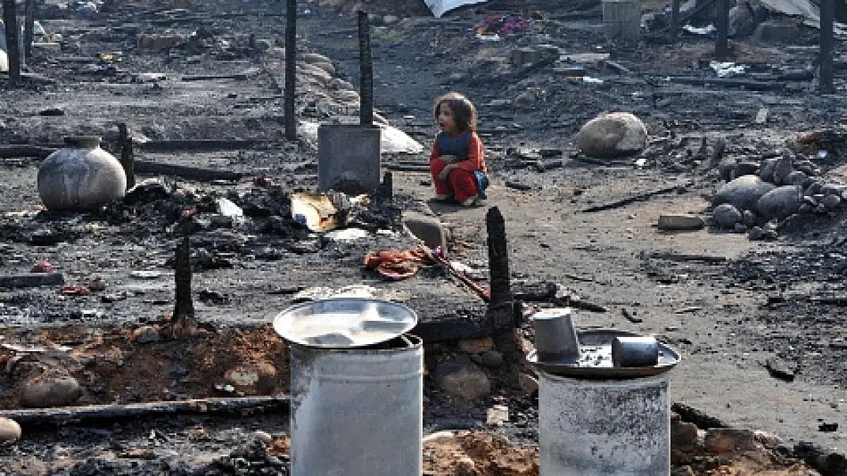 A Myanmar refugee lady looks for belongings after a fire at slum area outskirts of Jammu, on Novembe