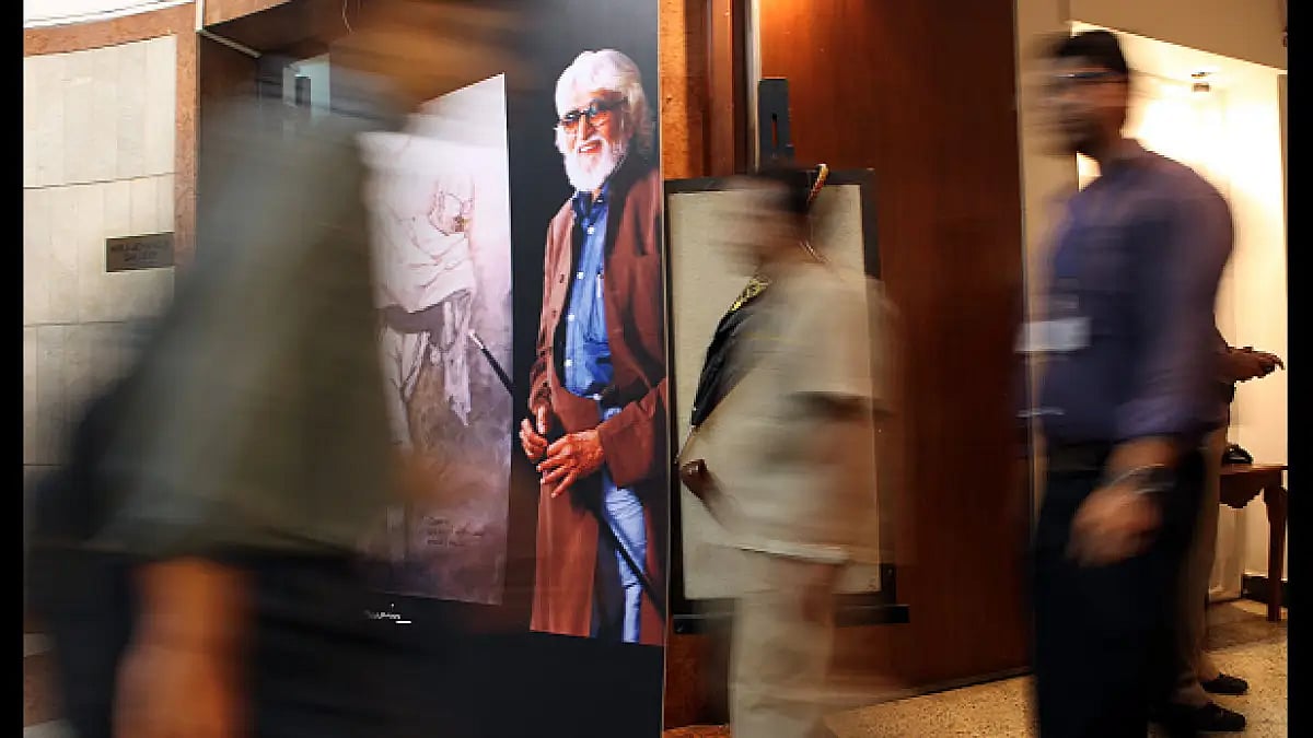 People pass by the poster of M.F. Hussain put up outside Jahangir Art Gallery during his condolence 