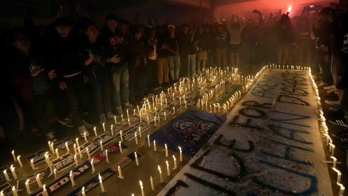 Football fans gather during a candle light vigil for Arema FC supporters who died in stampede.