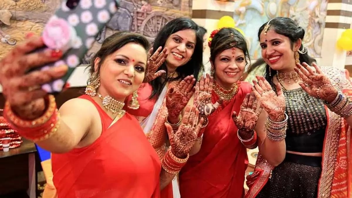 Women posing with Mehendi on their hands.