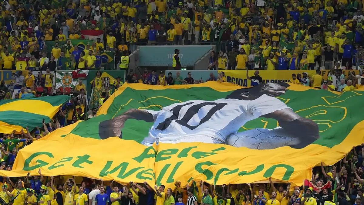 Fans display a flag with Pele's picture with a message that reads 'Pele, Get well soon.'