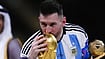 Lionel Messi kissing the World Cup trophy at Lusail Stadium, Qatar