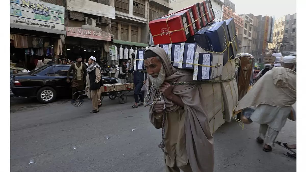 Pakistan Economic Woes: A laborer carries boxes through a market in Peshawar, Pakistan.