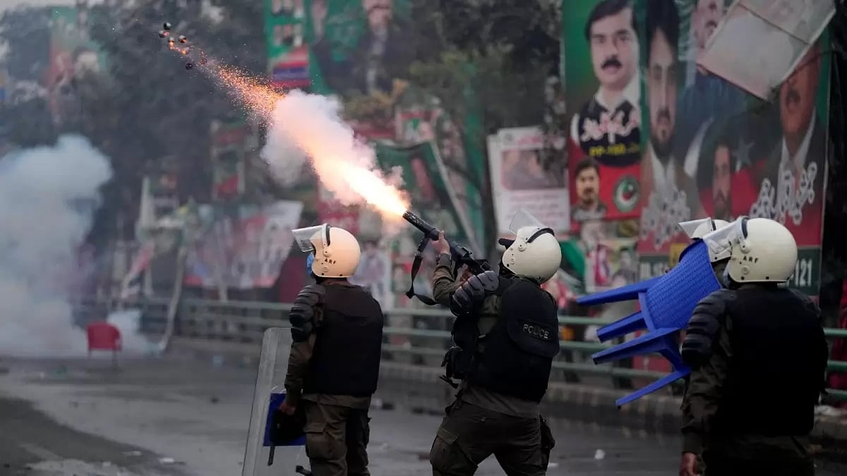 A riot police officer fires tear gas to disperse supporters of former Prime Minister Imran Khan during clashes outside Khan's residence, in Lahore, Pakistan, Tuesday, March 14, 2023.